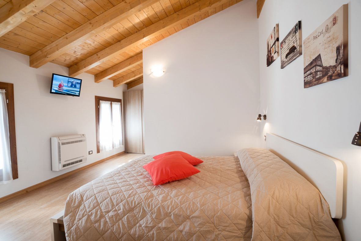 A bedroom with a bed, a television on the wall, and a poster.
