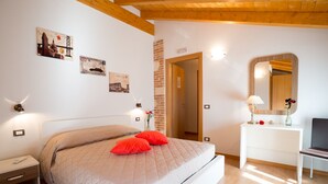 Un dormitorio con cama, mesita de noche, cómoda, espejo y lámparas fijadas a la pared.