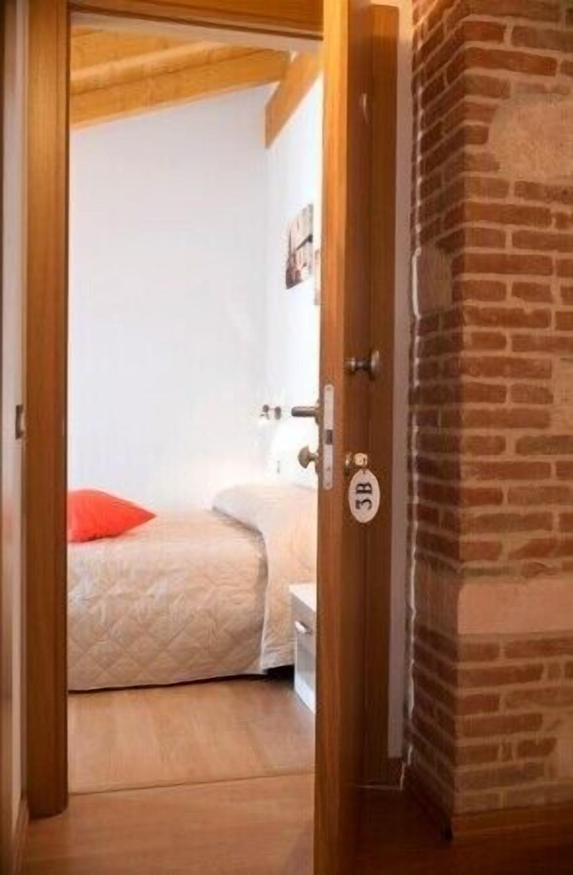 A bedroom with a bed, a nightstand, and a door with a number plate.
