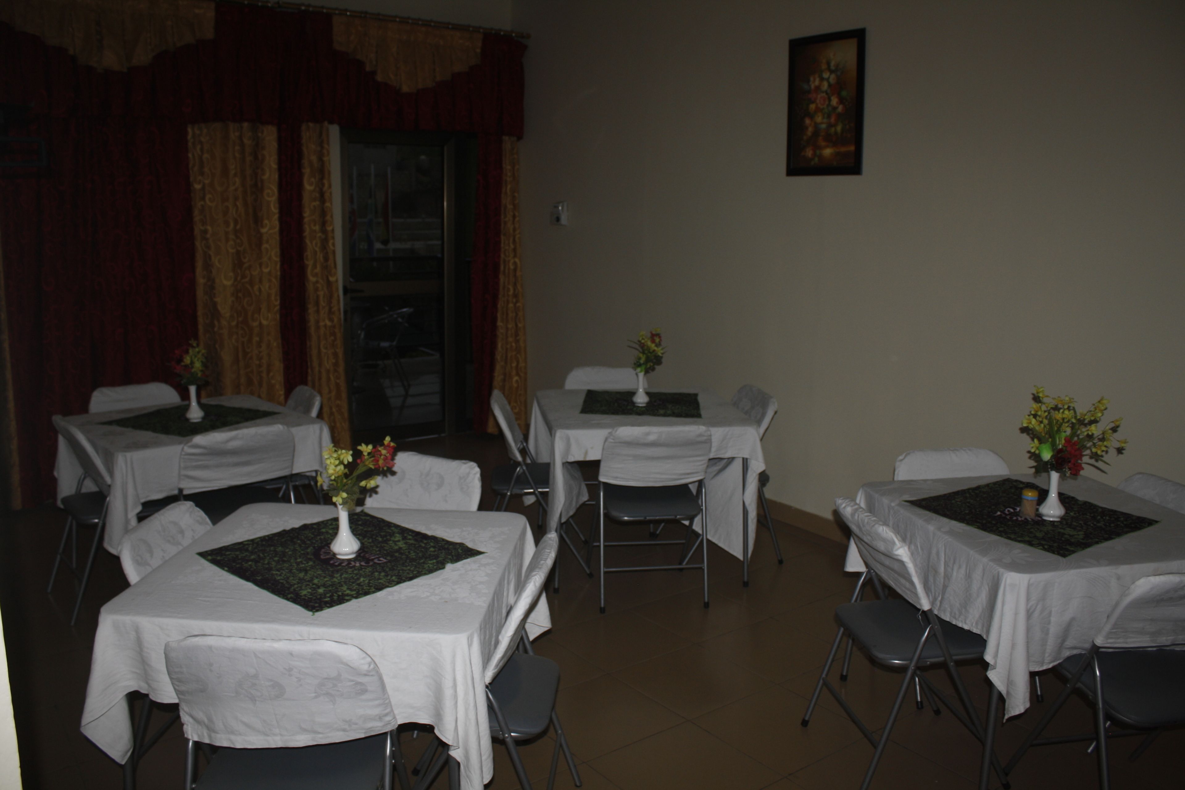 A conference room with tables set for meetings, each with a white tablecloth and a vase of flowers.