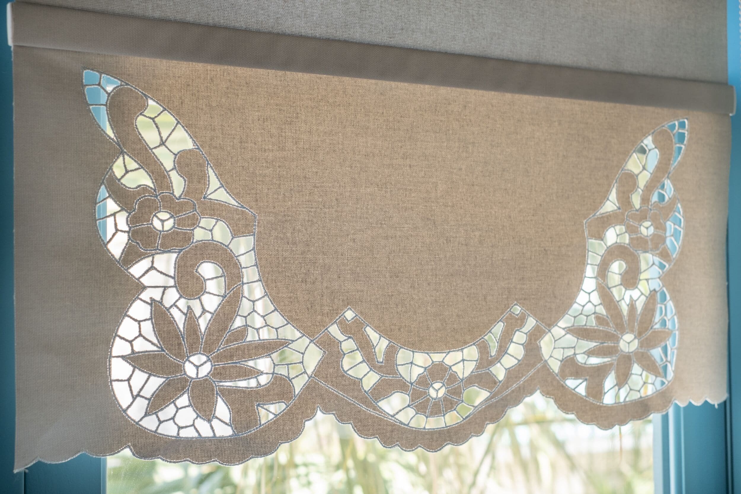 A window with a beige curtain featuring a stained glass butterfly design.