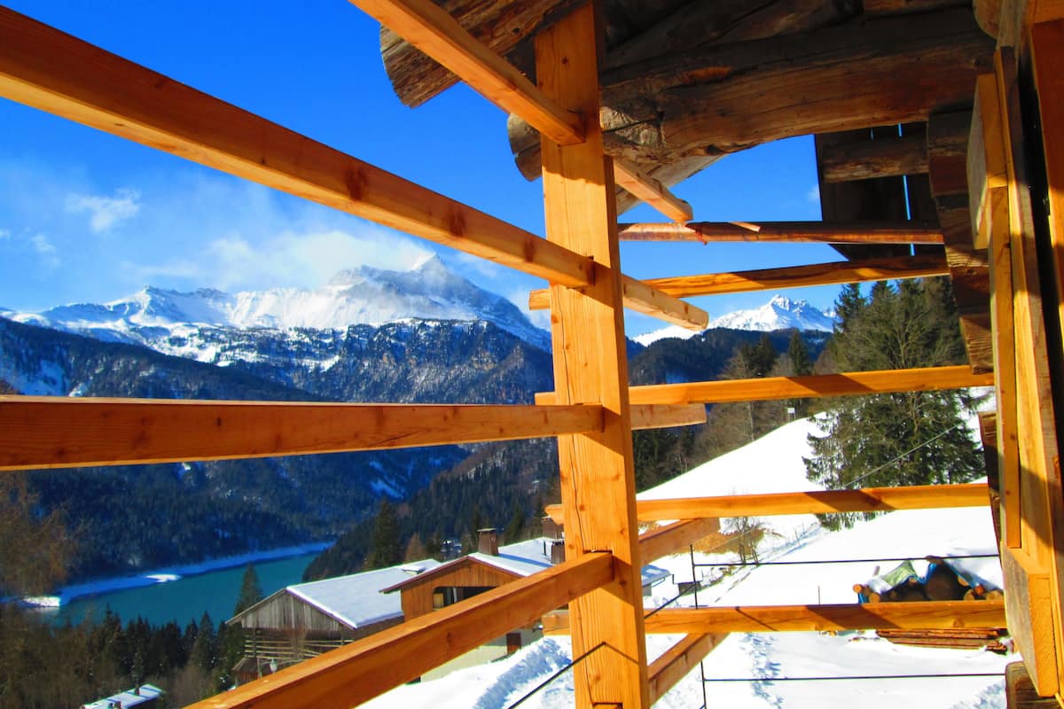 A wooden cabin structure with a view of snow-covered mountains and a lake.