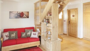 A cozy living room with a red sofa, wooden shelves, and a staircase.
