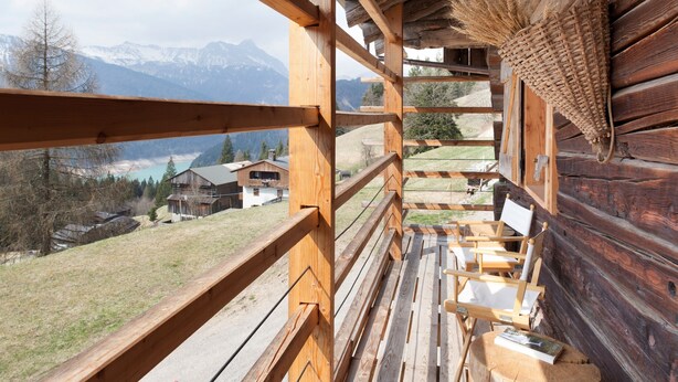 A wooden cabin with a balcony overlooking a mountainous landscape.