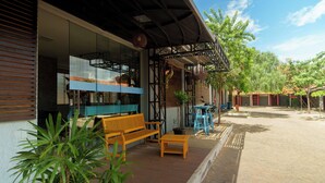 An outdoor seating area with a wooden bench and a small table, surrounded by potted plants and a covered patio. - W4 Hotel (Irece)