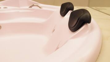 A bathroom with a bathtub, a faucet, and a control panel.