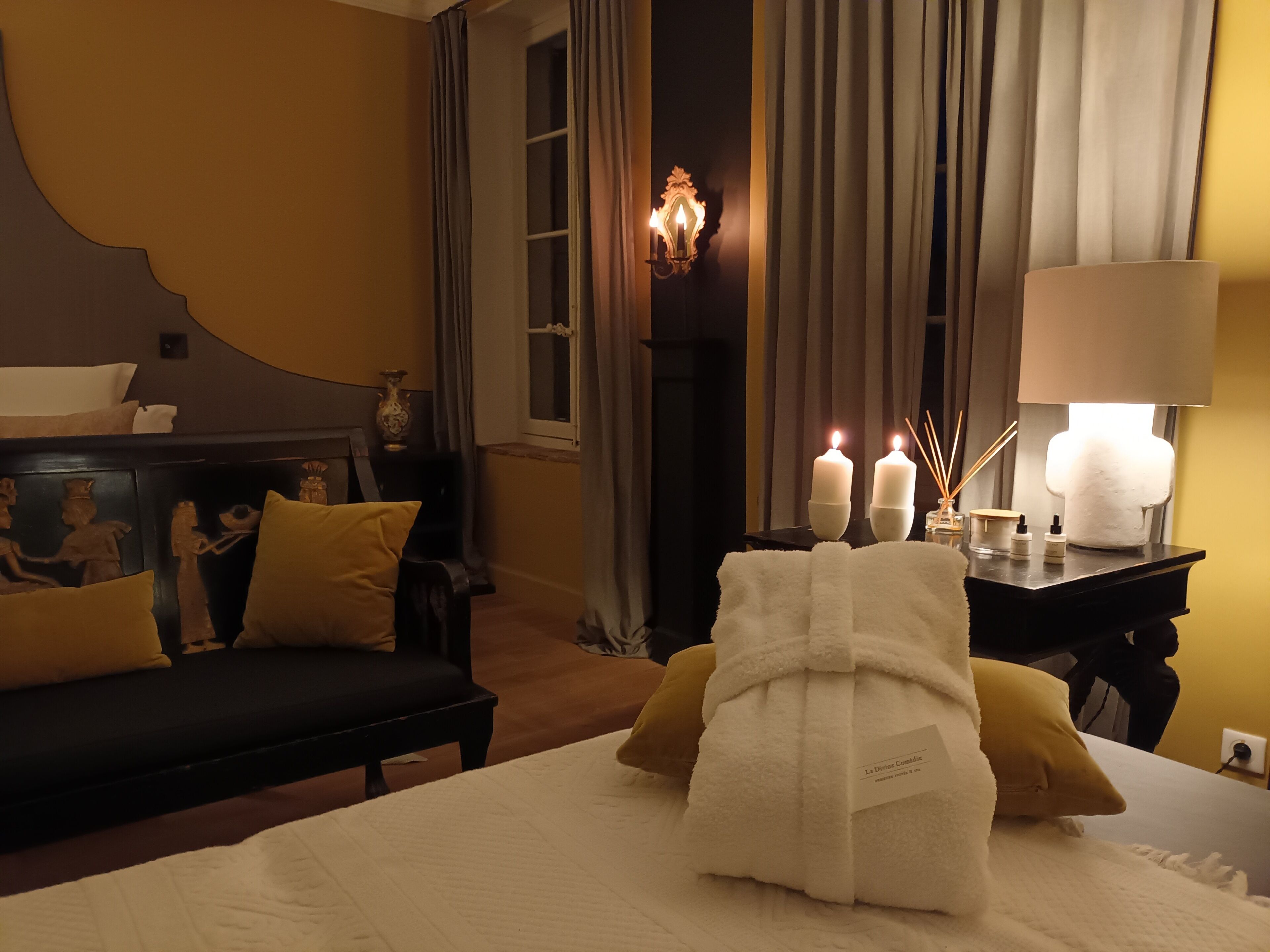 Una habitación de hotel con una cama, un sofá, una mesita de noche con velas y una lámpara.