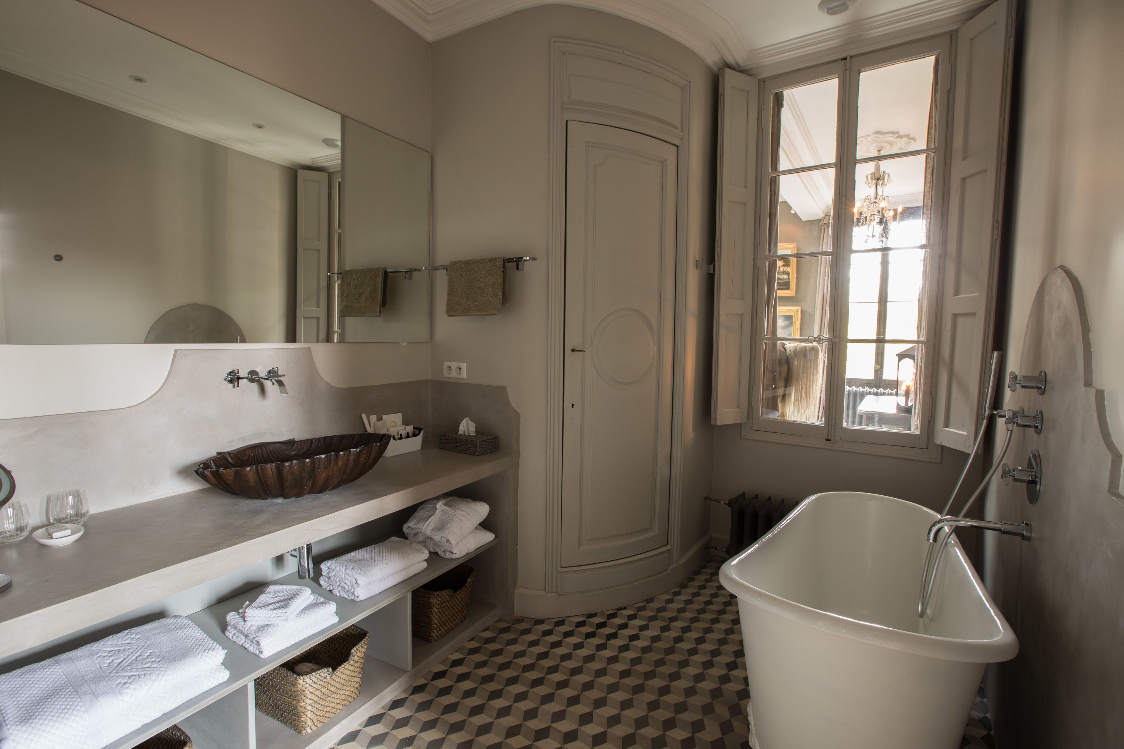 A bathroom with a large bathtub, a sink with a bowl, and a mirror.