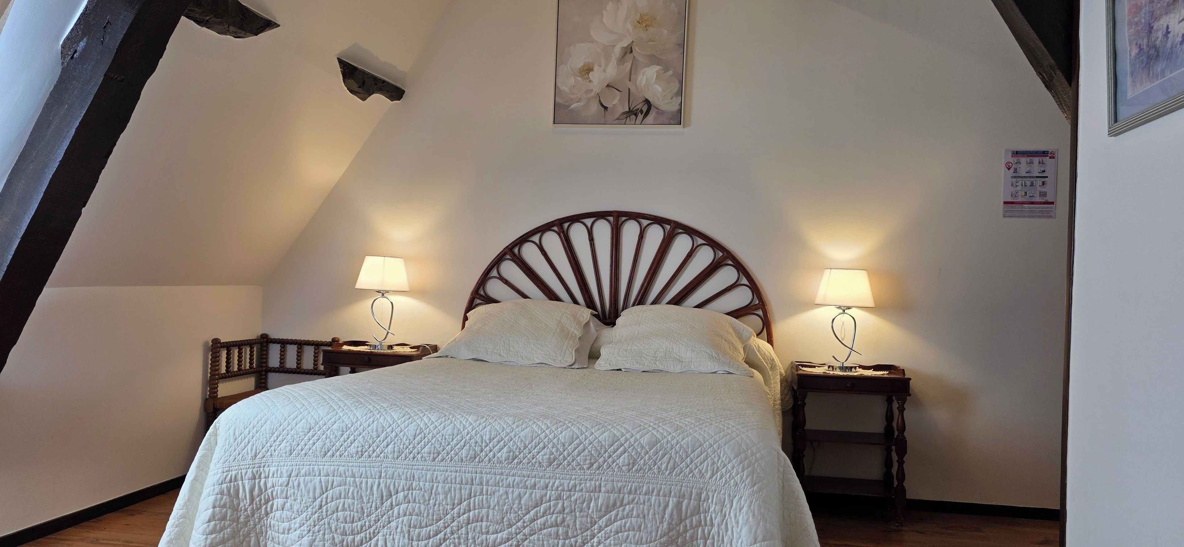Une chambre à coucher avec un lit, deux tables de chevet avec des lampes, une tête de lit en bois et un tableau au mur.