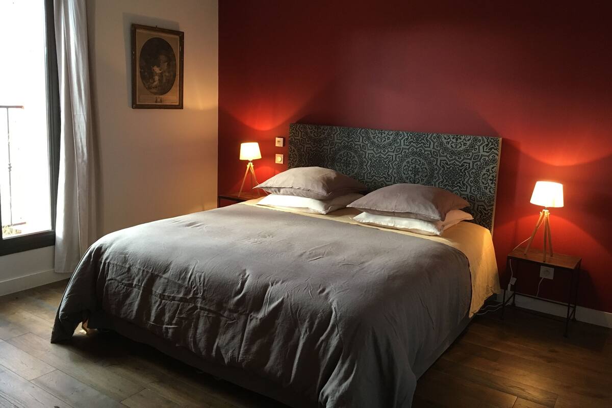 A neatly made bed with a headboard, two bedside lamps, and a framed picture on the wall.