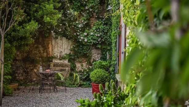 A garden patio with a table and chairs, surrounded by various plants and a stone wall. - Clos des Aspres (Ortaffa)