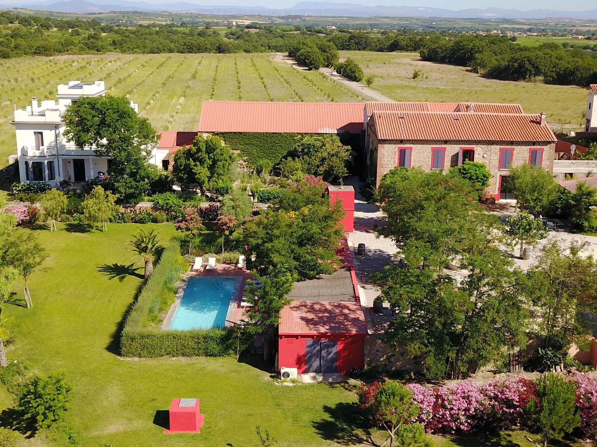 A large estate with a swimming pool, lush gardens, and multiple buildings.