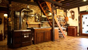A rustic kitchen with a brick wall, wooden beams, a stove, and a sign indicating a bakery. - La Maréchalerie (Monthodon)