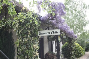 Ein Schild mit der Aufschrift 'Chambres d'hôtes' und ein Gebäude im Hintergrund.