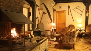 A cozy room with a fireplace, wooden furniture, and a brick wall. - La Maréchalerie (Monthodon)