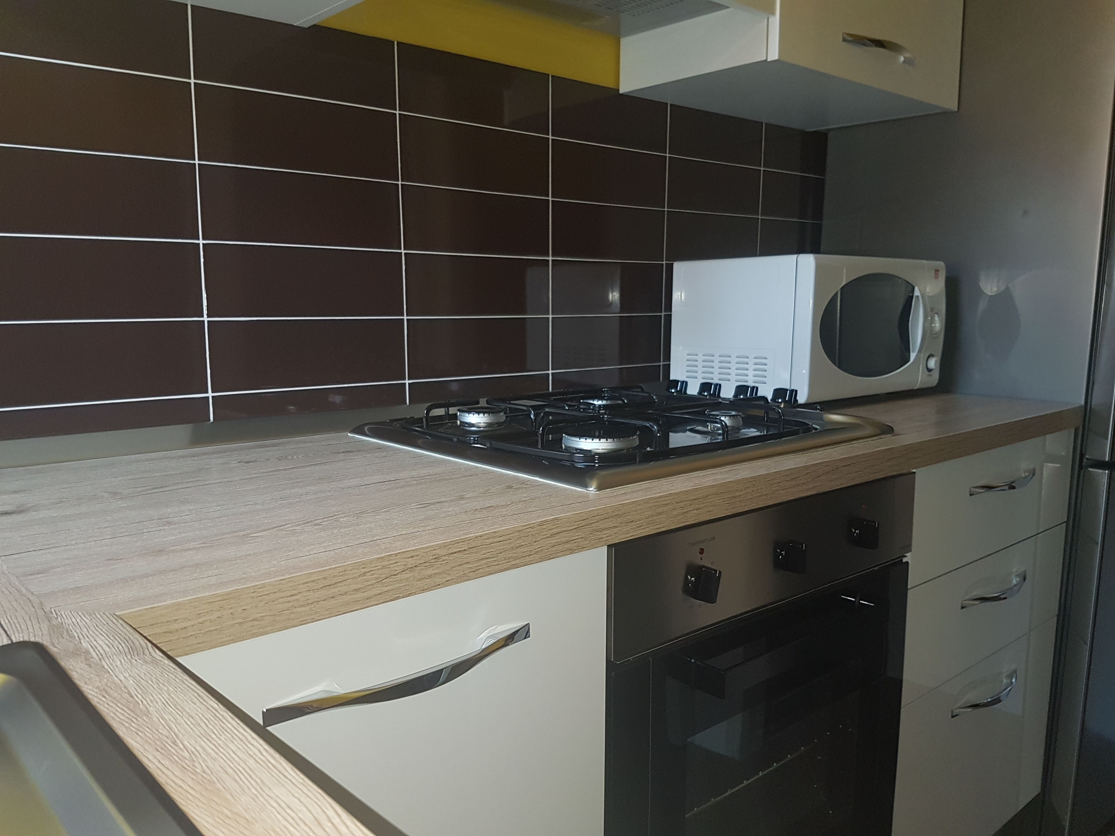 A kitchen with a gas stove, microwave, and stainless steel oven.
