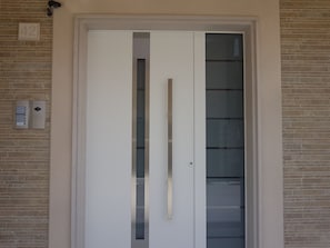 Una puerta blanca con un picaporte vertical, un panel de vidrio y un letrero con el número 42 en la pared.