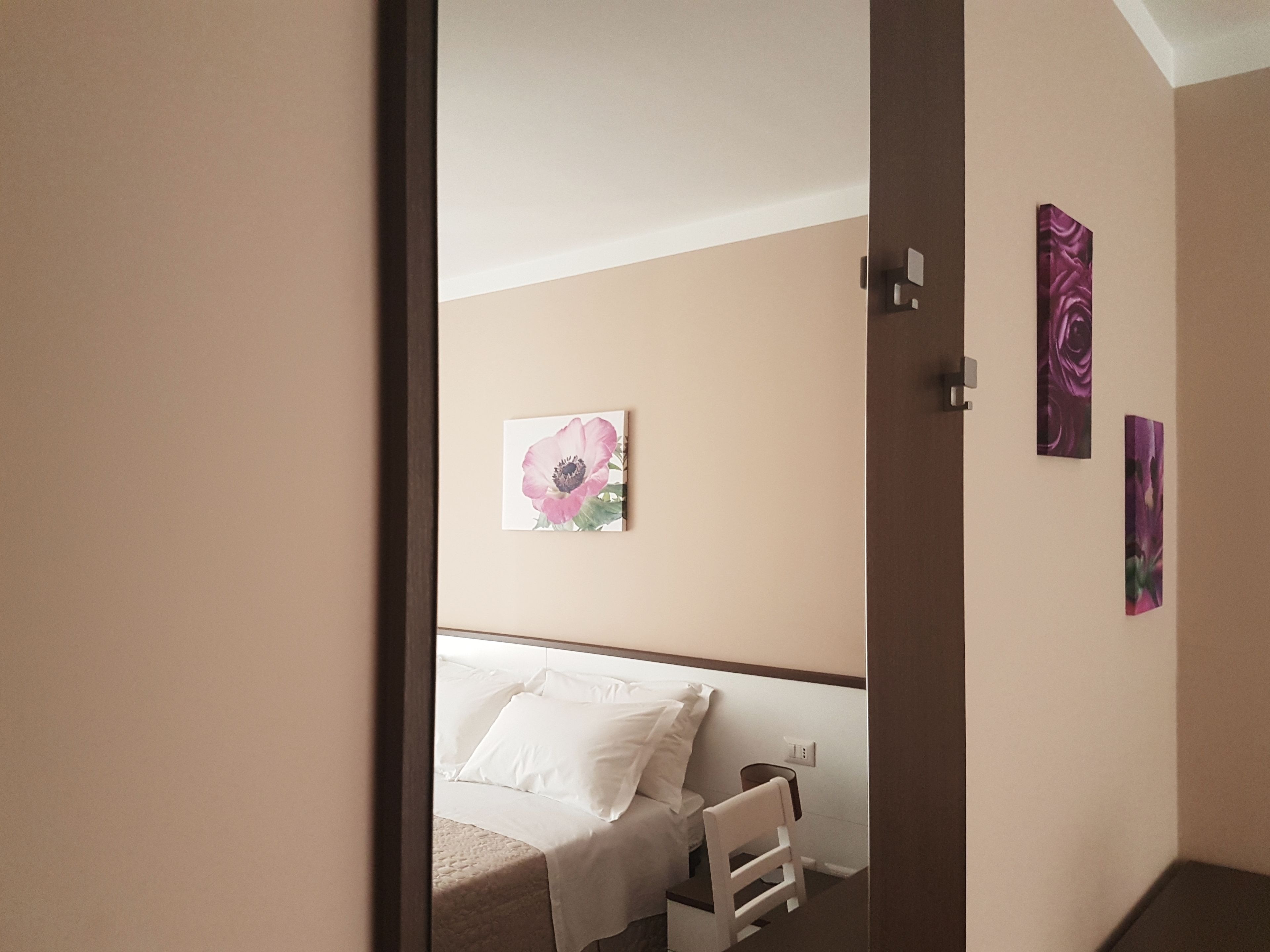 Un dormitorio con una cama, una silla y una pared con tres cuadros.