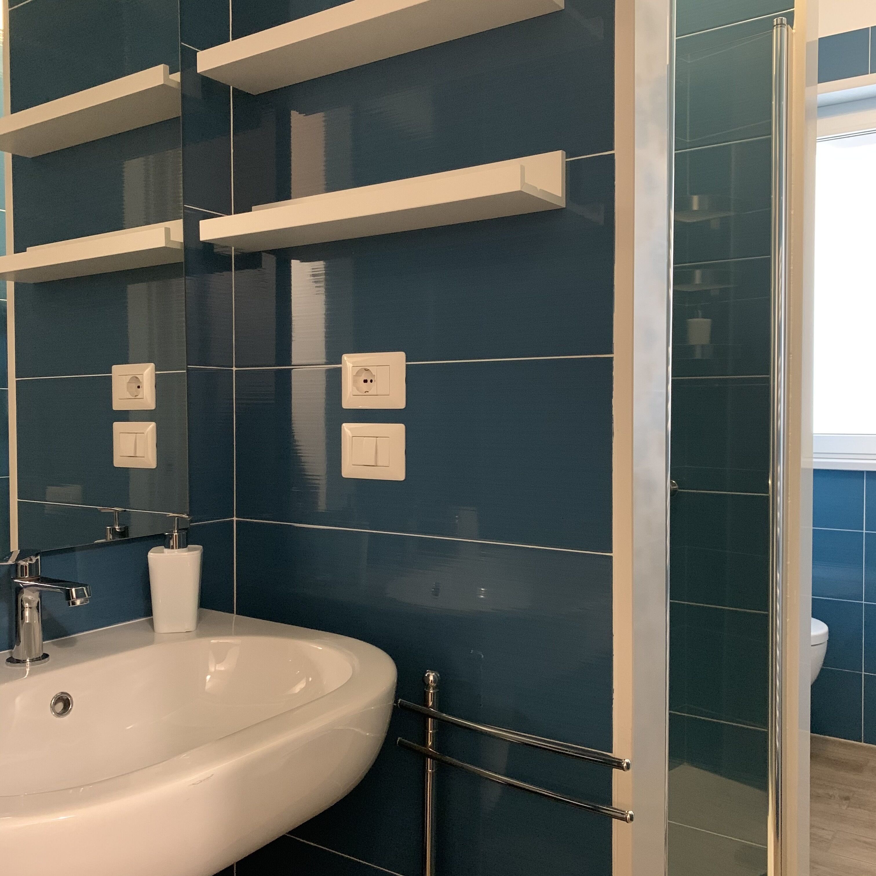 A bathroom with a white sink, a mirror, and blue-tiled walls.