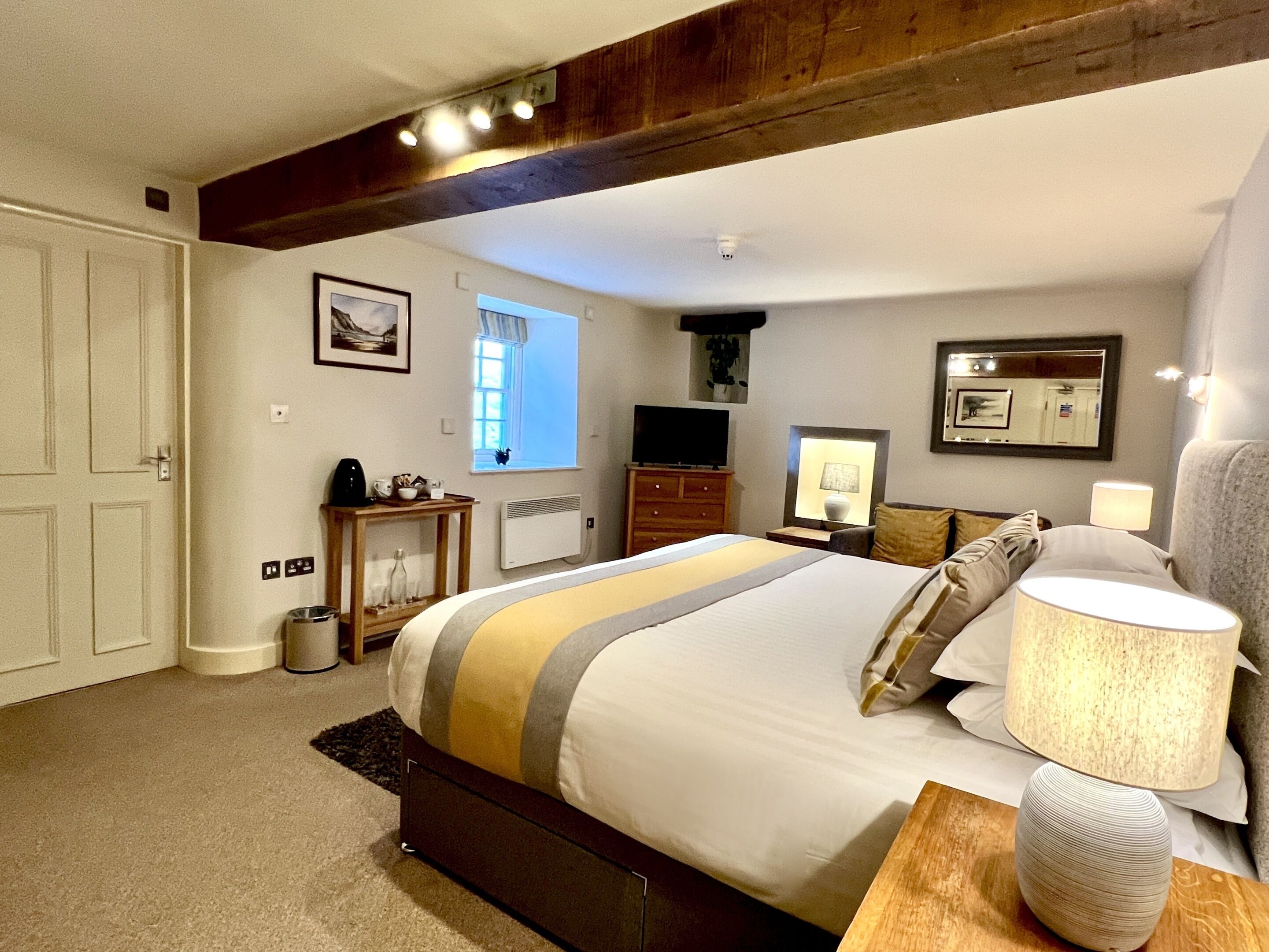 A bedroom with a bed, bedside tables, a dresser, a television, and a window.
