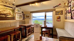 A cozy room with wooden furniture, a wine list sign, and a scenic view through the window. - Castle Cottage Inn (Harlech)