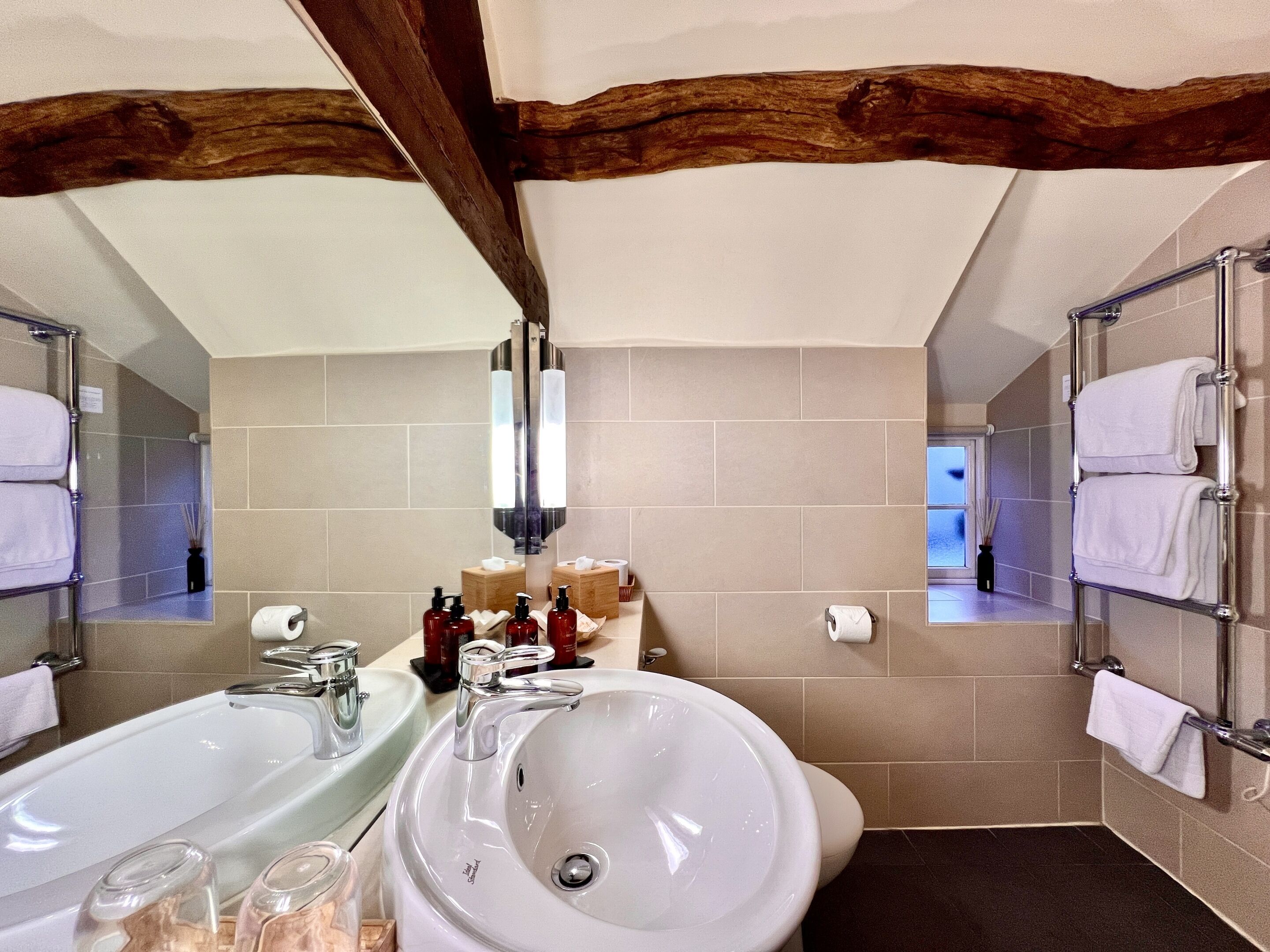 A bathroom with two sinks, a mirror, and a towel rack.