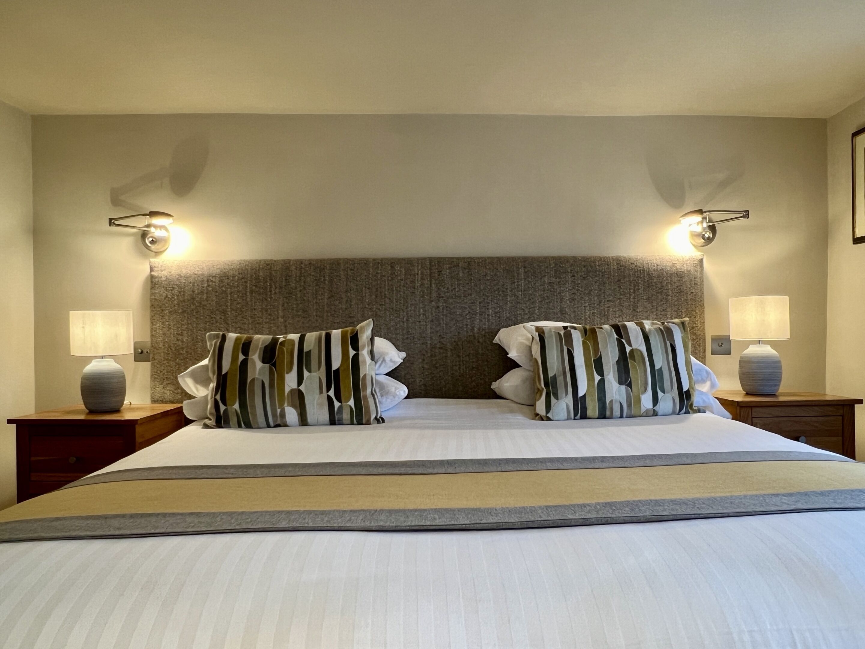 Een hotelkamer met een groot bed, twee nachtkastjes en wandlampen.