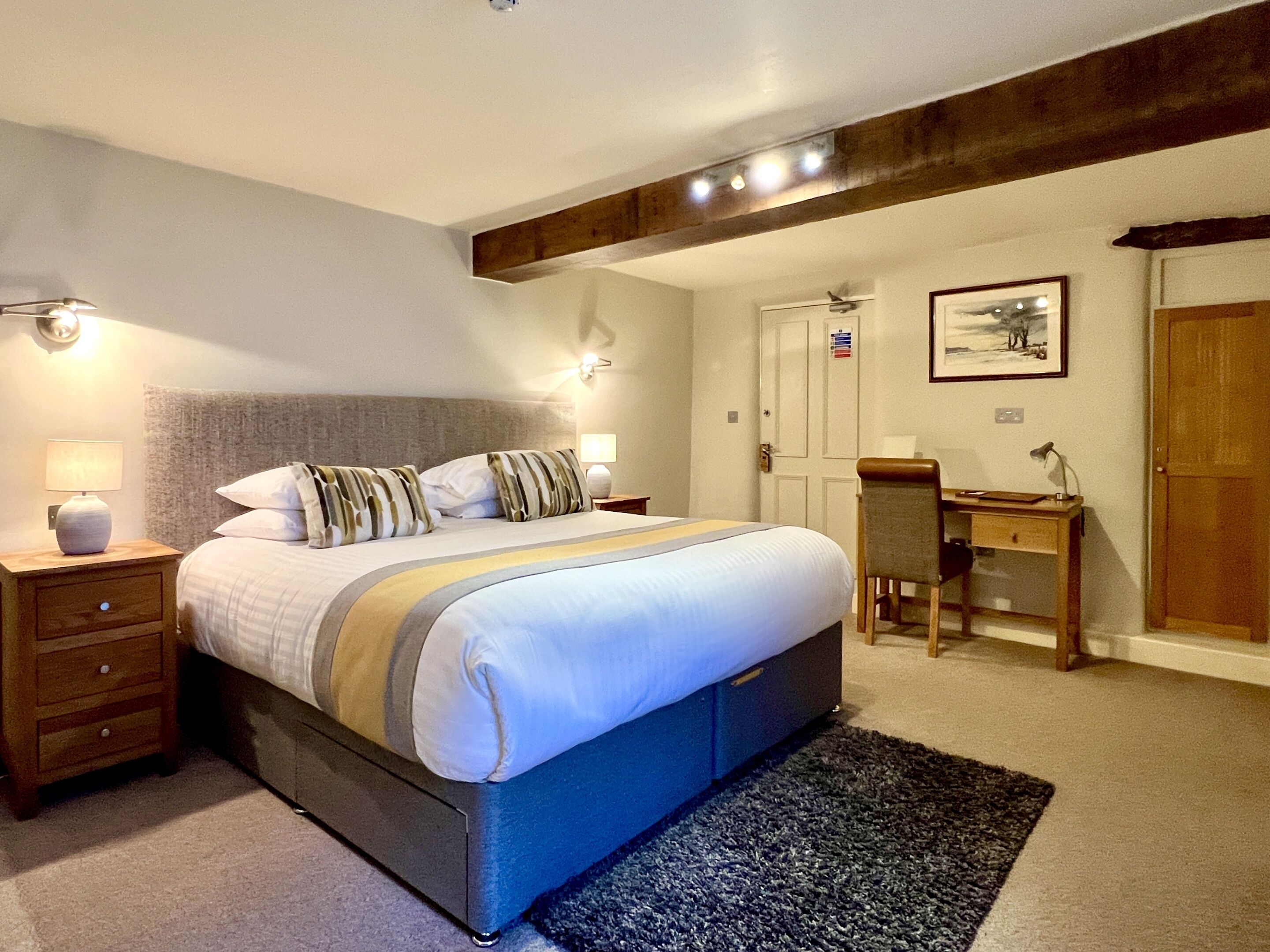 A bedroom with a large bed, bedside tables, a desk, and a chair.