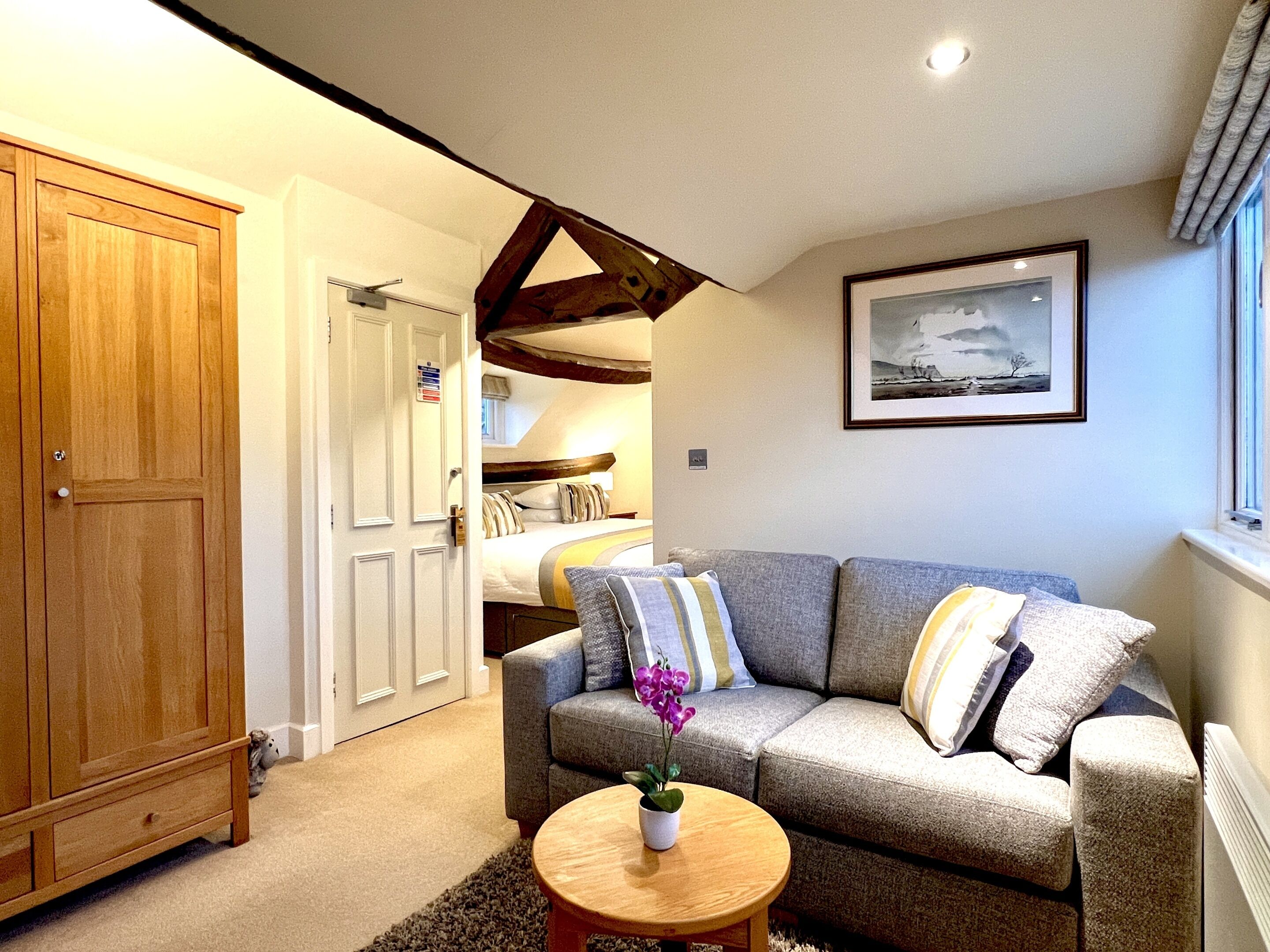 A cozy living room with a grey sofa, a wooden coffee table, and a framed picture on the wall.