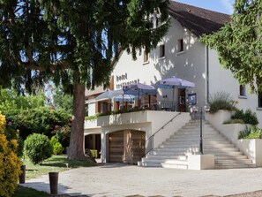 A hotel with a staircase leading to the entrance, outdoor umbrellas, and a well-maintained garden. - Hôtel Restaurant La Bonne Etape (Amboise)