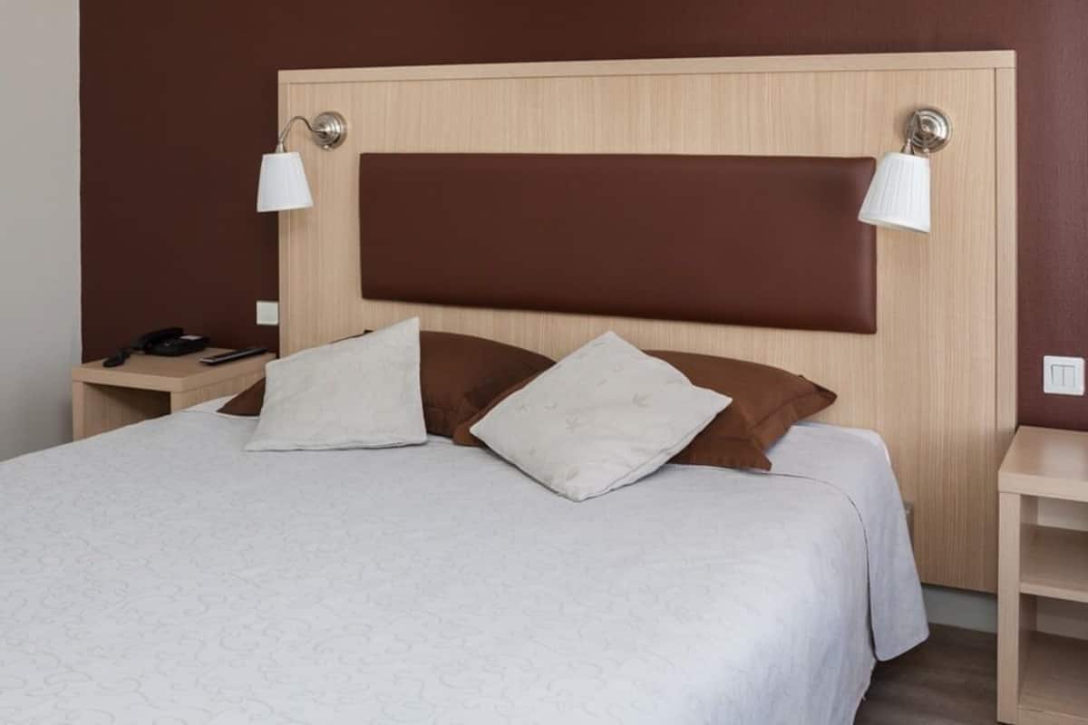 Une chambre d’hôtel avec un grand lit, deux lampes de chevet et une tête de lit en bois.