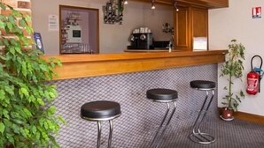 A bar area with a wooden counter, three stools, a fire extinguisher, and a potted plant. - Hôtel Restaurant La Bonne Etape (Amboise)