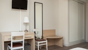 A hotel room with a desk, two chairs, a bed, a TV, a mirror, and a wardrobe. - Hôtel Restaurant La Bonne Etape (Amboise)