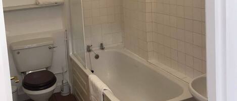 Une salle de bain comprenant des toilettes, une baignoire et un espace douche.