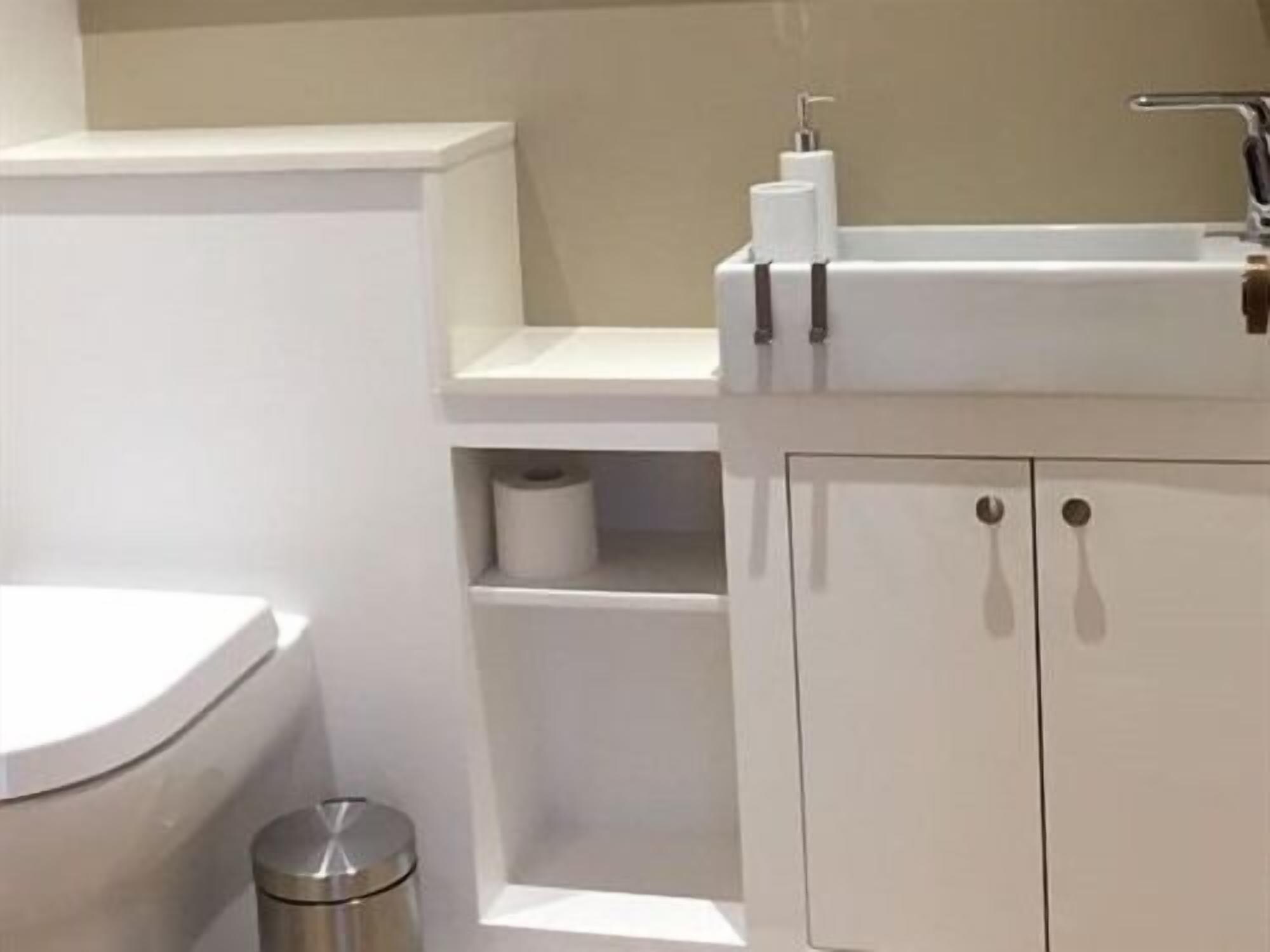 A modern bathroom with a toilet, sink, and storage cabinet.