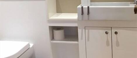 A modern bathroom with a toilet, sink, and storage cabinet.