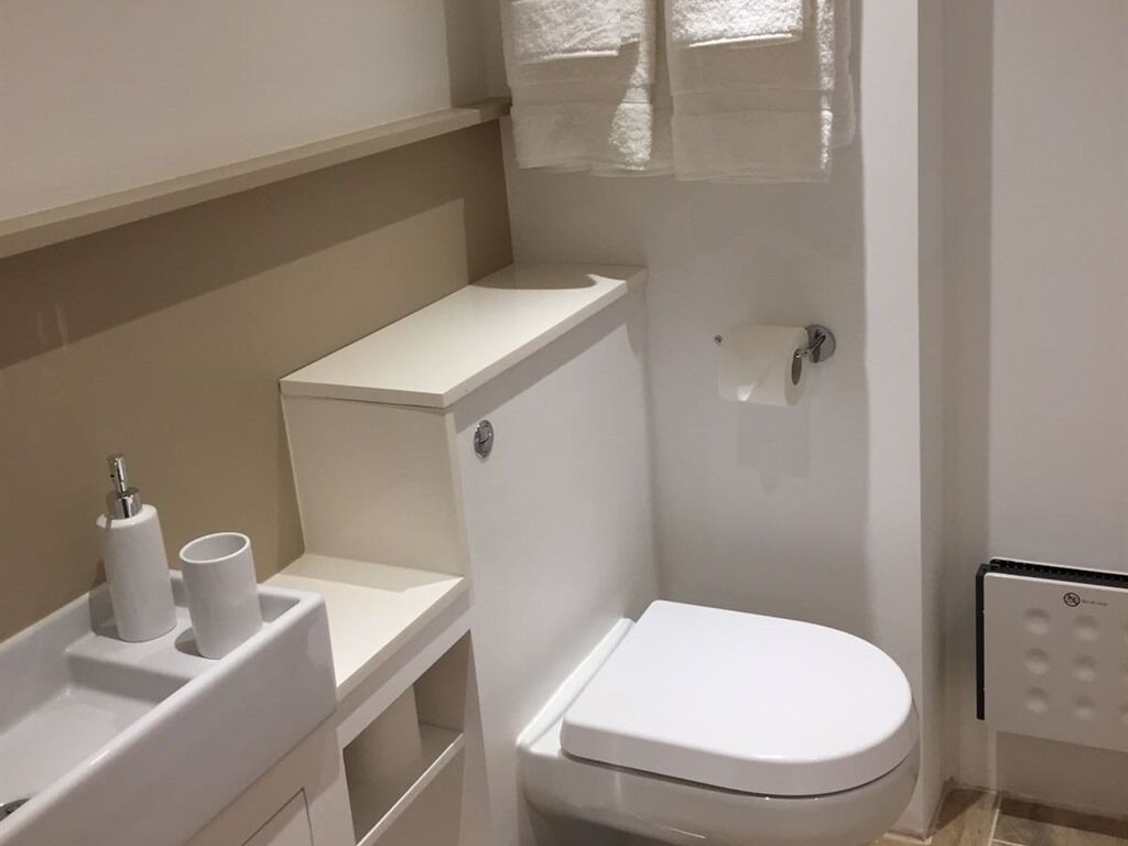 Ein kleines, weißes Badezimmer mit Toilette, Waschbecken und Handtuchhalter.