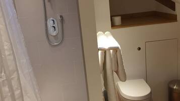 A bathroom with a shower, toilet, and a towel rack.