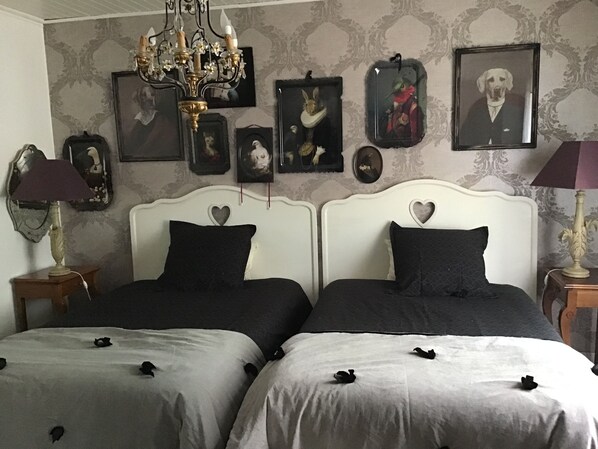 A bedroom with two beds, a chandelier, and framed pictures on the wall. - La Guinière Chambres D'hôtes (Coueron)