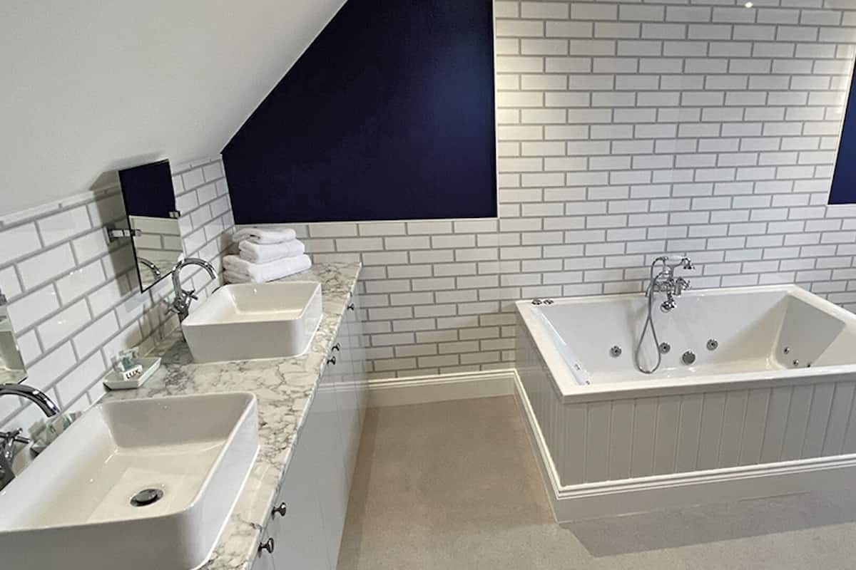 A modern bathroom with two sinks, a bathtub, and a toilet.
