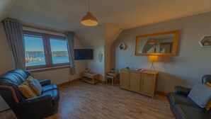 Una sala de estar con vista al mar, un sofá, un aparador y una lámpara.