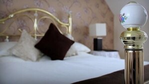 Una cama con cabecera dorada, ropa de cama blanca y almohada marrón oscuro.
