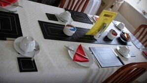 Una mesa de comedor dispuesta con platos, cubiertos y una carta.