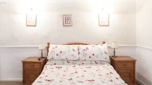A bedroom with a bed, two nightstands, and three wall-mounted picture frames. - The Willow Restaurant B&B (Harrogate)