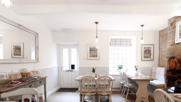 A dining area with white chairs, a wooden table, and a buffet with covered dishes. - The Willow Restaurant B&B (Harrogate)