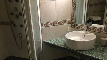 Ein Badezimmer mit Dusche, Waschbecken und Spiegel.
