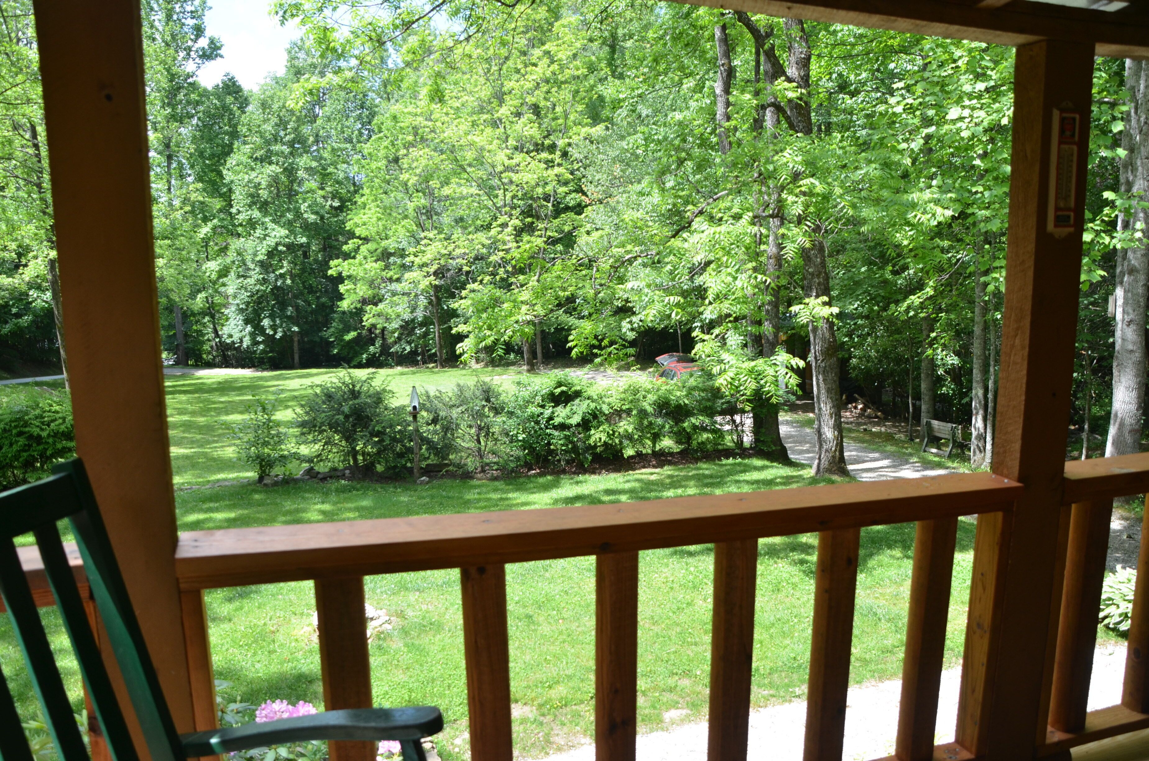 A wooden deck with a view of a well-maintained garden and a path leading to a bench.