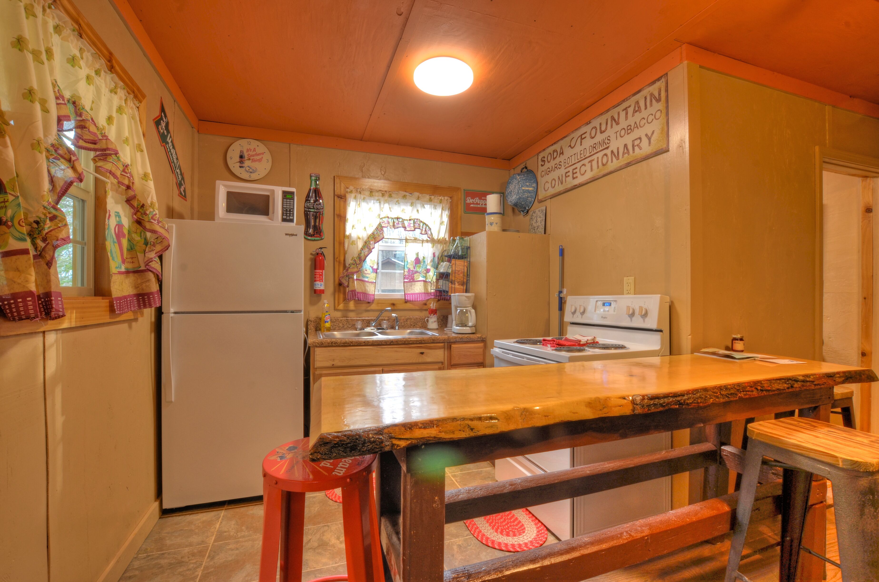 A kitchen with a wooden countertop, a refrigerator, a sink, and a microwave.