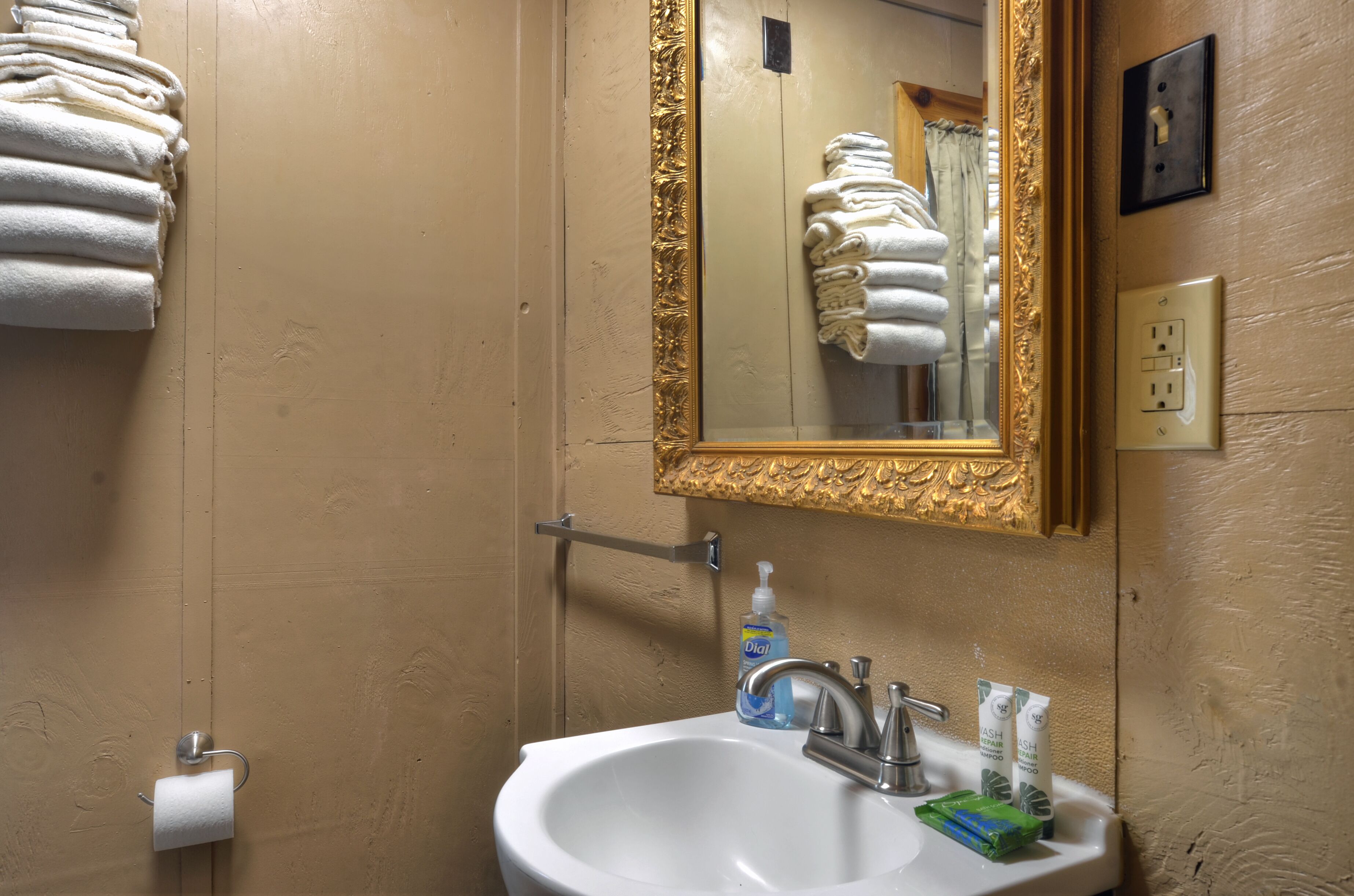 Une salle de bain équipée d’un lavabo, d’un miroir, d’un porte-serviettes et d’articles de toilette.
