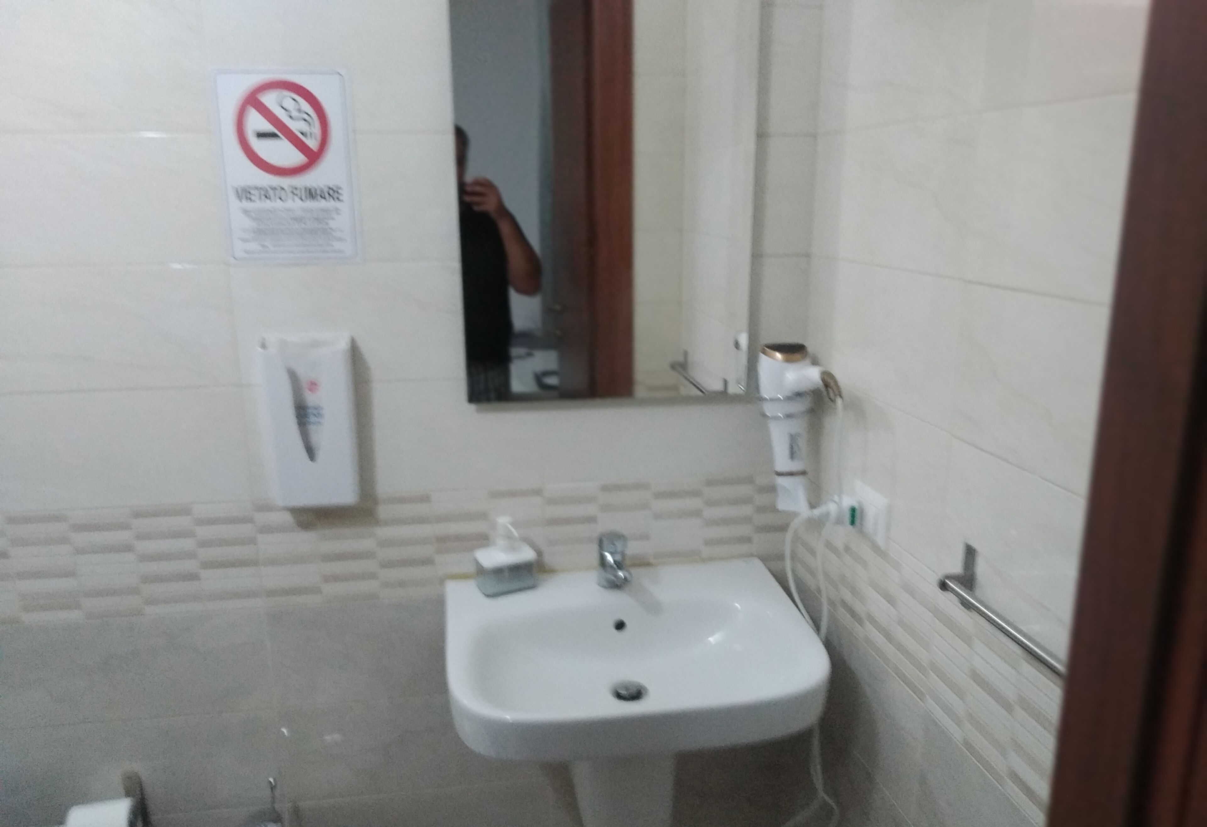 Une salle de bain équipée d’un lavabo, d’un miroir et d’un panneau indiquant qu’il est interdit de fumer.